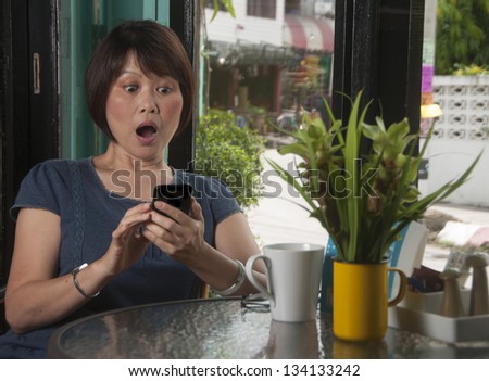 Mature Asian woman getting message on smartphone