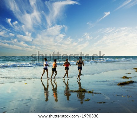 four women go jogging on the beach along the waters edge four women go jogging on the beach along the waters edge