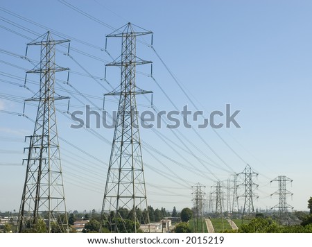 a group of high voltage power towers and electrical lines going over a hill from the power station