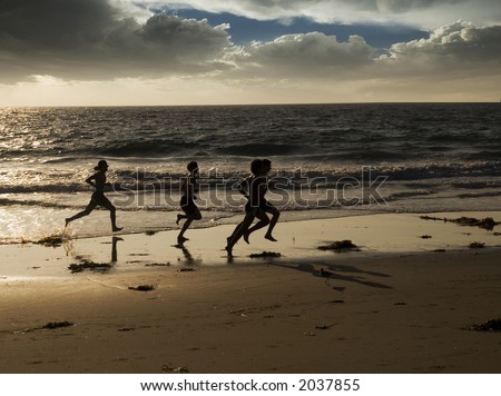 a group of four young men are jogging along the waters edge at the beach for exercise.
