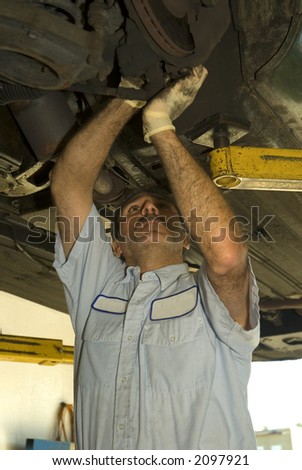 auto repair mechanic inspects the undercarriage of an automobile
