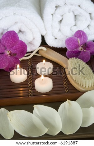 Body brush on a bamboo tray with candles and towels