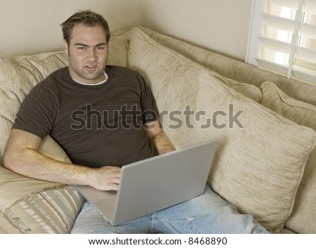 young man laying on sofa using laptop computer
