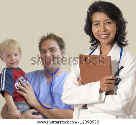 Smiling and confident female Asian Doctor and male intern holding child.