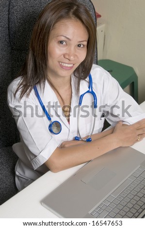 Smiling and attractive female Asian Doctor sitting at her desk