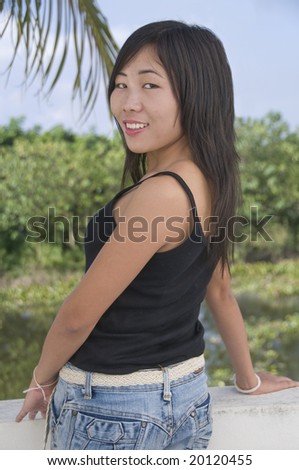 Modern looking Asian woman looking over her shoulder at camera