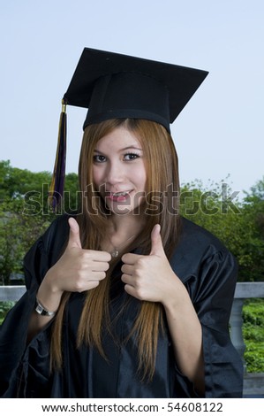 Young woman with graduation cap and gown and two thumbs up
