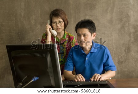 Asian businessman sitting at computer in modern office with co-worker