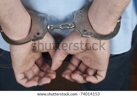 A mans hands in handcuffs behind his back