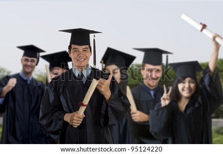 Young man wearing graduation cap and gown with classmates