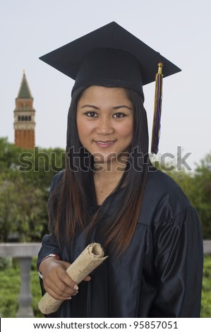 Young woman with graduation cap and gown holding diploma