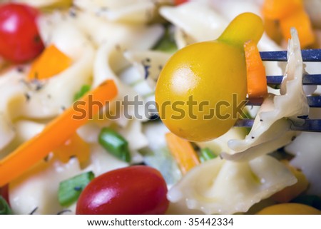 Pasta with a yellow pear tomato on a fork as the focal point
