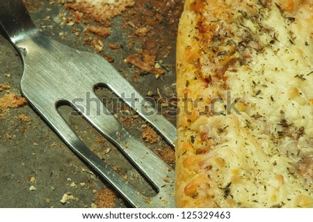 Closeup of grungy pizza pan, with pizza and serving utensil.