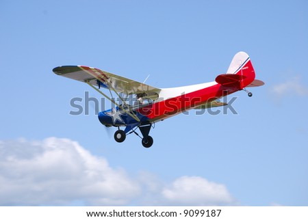 Vintage personal aircraft with red white and blue paint scheme against sky background.