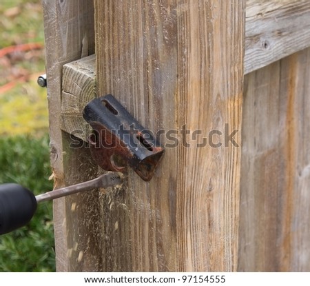 Hand drill with wood bit drilling hole in post.