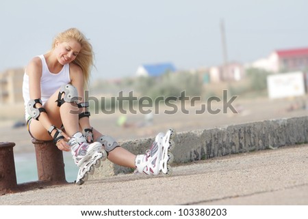 young smiling woman getting ready for rollerblading / roller skating on natural background