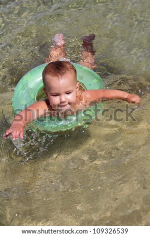 outdoor portrait of happy baby swimming in swim trainer