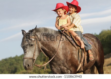 two happy children riding horse on natural background