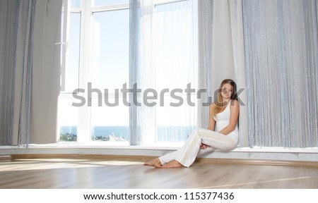 young happy smiling woman next to big window at home / hotel