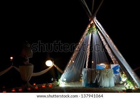 wedding arch and set up with flowers on tropical beach at night