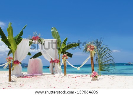 wedding arch and set up with flowers on tropical beach under palm trees