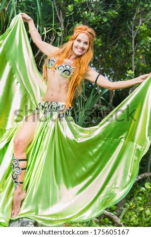 young beautiful woman in traditional arabic clothes, belly-dancer on natural background