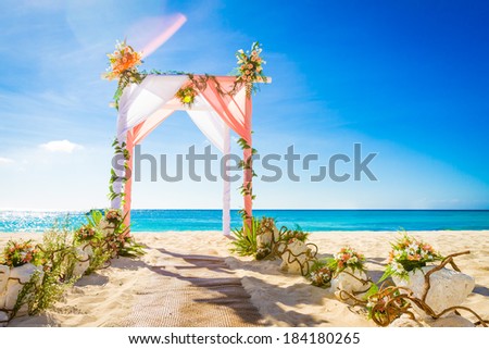 wedding arch decorated with flowers on tropical sand beach, outdoor beach wedding setup