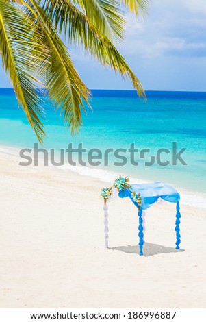 wedding arch decorated with flowers on tropical sand beach, outdoor beach wedding setup