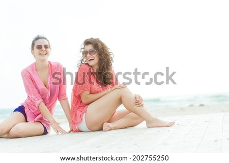 two young happy women enjoying life outdoors on sea background