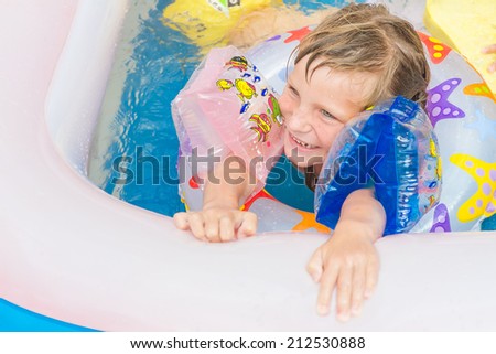 young happy child girl swimming in pool with swimming ring