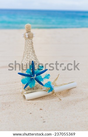 decorated glass bottle and paper letter note on tropical sand beach