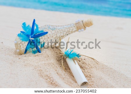 decorated glass bottle and paper letter note on tropical sand beach