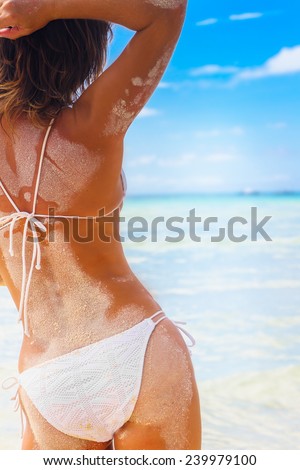 young beautiful woman enjoying sunbathing in the sea on tropical beach, summer vacations