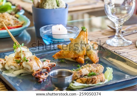 seafood snacks, calamaris, squid rings served in outdoor restaurant, asian cuisine