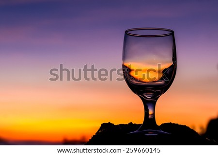 tropical sunset on beach reflected in a wine glass, summertime vacation concept