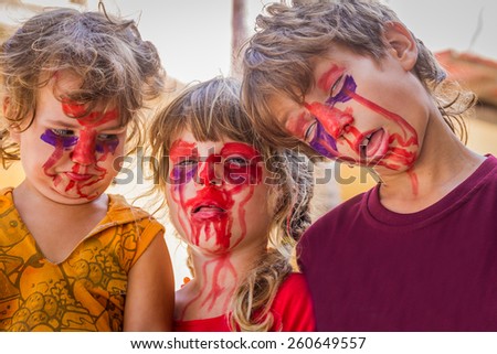 three young kids - boy and girl - with painted faces, child zombie face art