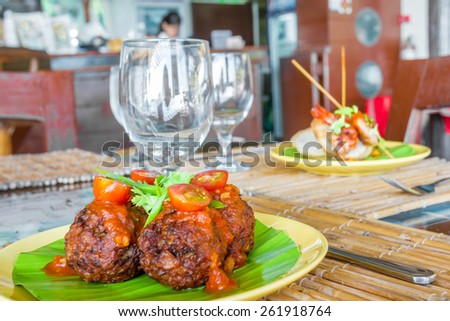 meat balls with tomato served on palm tree leaf
