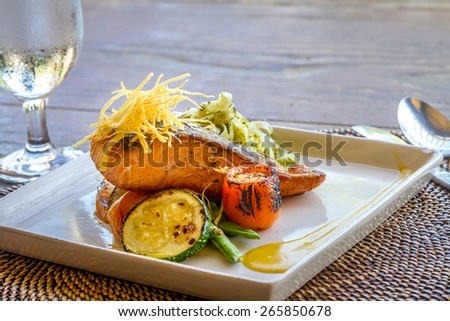 grilled salmon steak served with pasta and vegetables in a small outdoor restaurant
