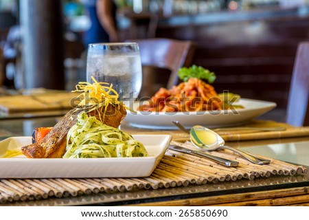 grilled salmon steak served with pasta and vegetables in a small outdoor restaurant