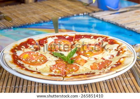 freshly baked pizza with cheese and tomatoes served in small outdoor restaurant, meal time