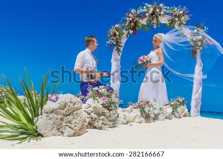 bride and groom enjoying beach wedding in tropics, on wedding arch, setup background