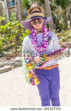 young happy groom having fun on wedding day with lots of hats and flowers in tropics