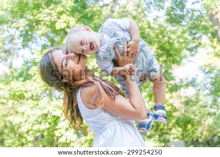 happy young mother with child - baby boy - outdoor portrait on green natural background