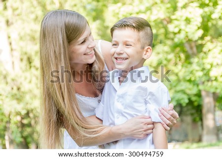 happy young mother with child - boy - outdoor portrait on green natural background