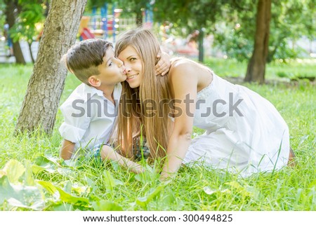 happy young mother with child - boy - outdoor portrait on green natural background