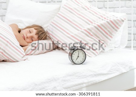 indoor portrait of young happy smiing child girl sleeping in her bed, happy morning time