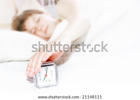 sleeping girl trying to turn off the alarm clock, focus on clock