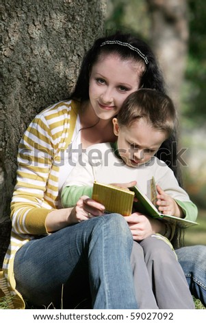 mother and son reading book outdoors