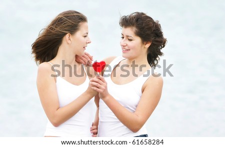 two girls with heart-shaped candy on natural background