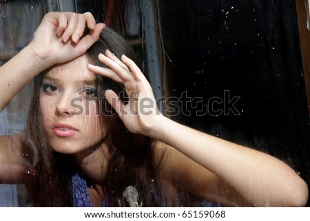 portrait of young girl behind wet window
